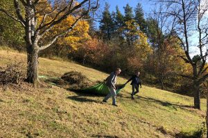zwei Menschen mit einer Plane auf einer herbstlichen Wiese