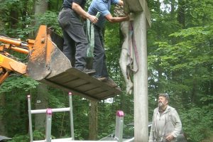 Männer reparieren ein großes Steinkreuz