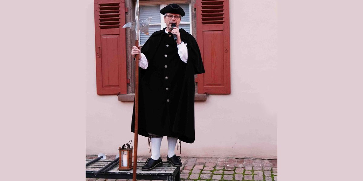 Mann mit Mikrofon in der Hand steht auf einem Stuhl