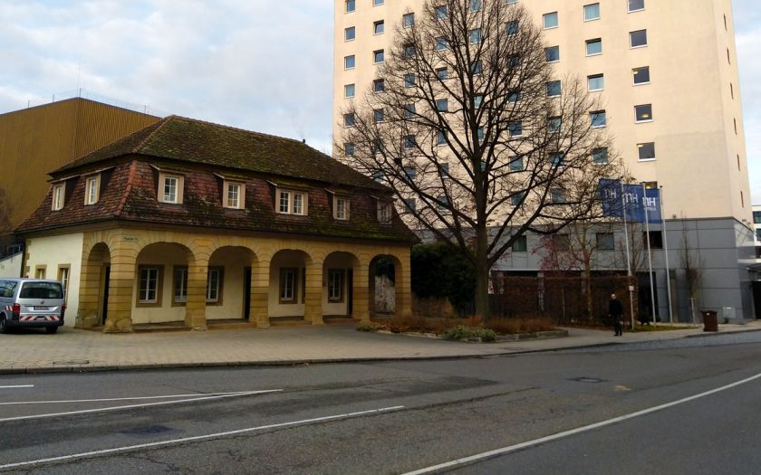 kleines historisches Gebäude neben großem Hotelhochhaus