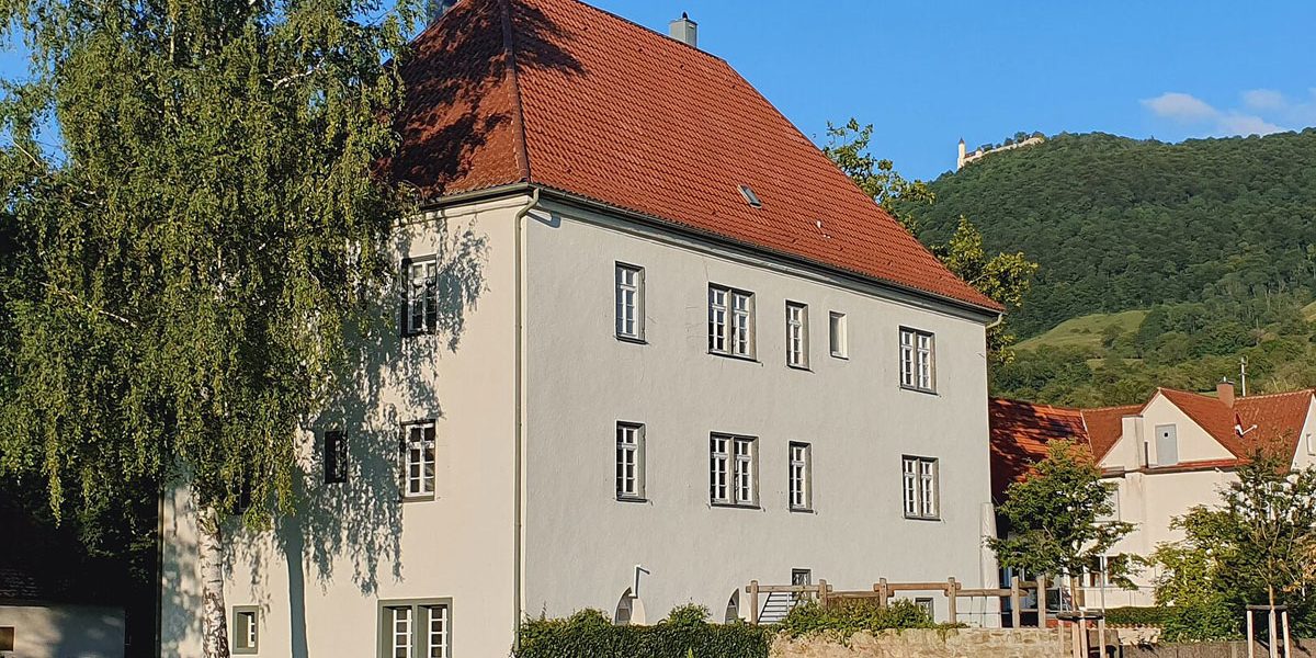 großes Gebäude in einer Stadt mit Burg im Hintergrund