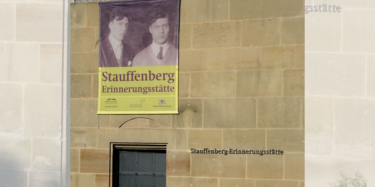 Plakat an einem Gebäude mit Eingangstür aus Metall